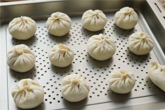 全部做好的包子，放在蒸烤箱的烤盘里，中间留有间隙，再松弛醒发20分钟左右。我放在蒸烤箱里面发酵，我用的是美的蒸烤箱，发酵时全是细密的蒸汽，特别赞。