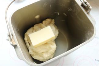 除了黄油之外，把其余的面团材料放入面包机，揉一个面团程序，这时面团达到初步扩展。再加入室温软化的黄油，继续揉一个面团程序。