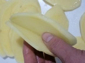 首先把土豆切成两片相连的薄片，如图