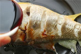 蒸熟的鱼，把姜片葱段拣出来，蒸鱼的汤也倒掉。把蒸好的鱼移到另一个盘子里，淋上生抽。