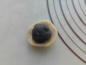 取一个水油皮剂子，按压扁，将油酥小剂子放入