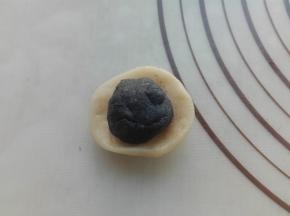 取一个水油皮剂子，按压扁，将油酥小剂子放入