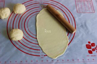 发酵好的面团压平，用擀面杖擀薄成椭圆形。