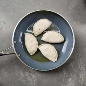 把锅烧热，倒少许的油润锅，下韭菜盒子煎一分钟左右，底部微黄翻面。