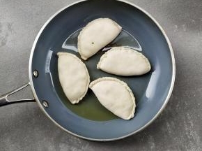 把锅烧热，倒少许的油润锅，下韭菜盒子煎一分钟左右，底部微黄翻面。