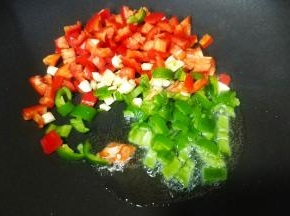 锅里热油，放入蒜、青、红椒快速翻炒。