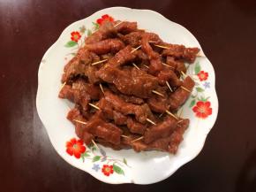用牙签将牛肉一根根串好，放在盘里。