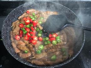 所有的肉都已变色，加入青红辣椒和蒜末翻炒均匀。