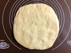 把面团放在揉面垫上按压排气。