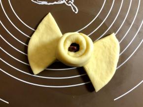 再取相对着的一瓣面片，继续把包好的部分裹起来，同样捏紧接口处。