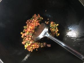 锅中倒入食用油，7成熟倒入豌豆，玉米，红萝卜翻炒几下，再放入火腿肠继续翻炒，最后倒入米饭，