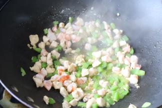 不粘锅内放入少许油，爆炒青椒粒，再放入鸡肉粒，炒至半熟后放入虾粒。