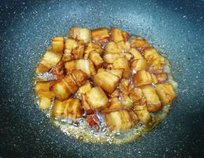 下入五花肉翻炒上色。