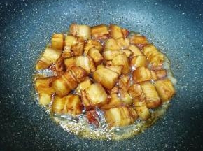 下入五花肉翻炒上色。