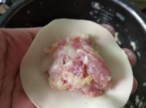 拿一张饺子皮，放入肉沫