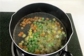 锅内加入适量清水煮沸，然后把玉米粒，胡萝卜粒和豌豆一起放入煮熟。