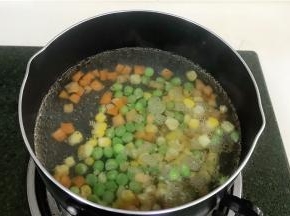 锅内加入适量清水煮沸，然后把玉米粒，胡萝卜粒和豌豆一起放入煮熟。
