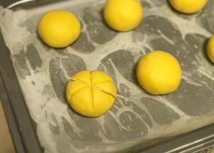 用牙签在面团上压出南瓜条纹，正中间再插上葡萄干，依次完成所有。