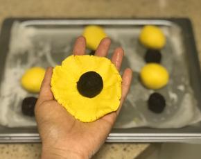 将南瓜面团擀成圆形面皮，放入一粒豆沙馅儿。