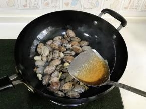 看到花蛤微微开口后，倒入2大匙料酒。