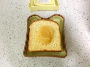 取一片吐司放在口袋三明治的模具上，中间抹上菠萝酱。