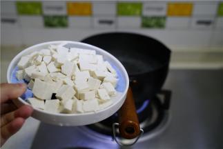 锅仔里加水煮开，将豆腐切丁下锅煮至浮起。