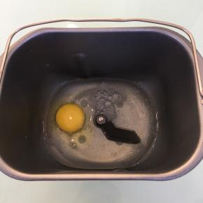 将清水，玉米油和鸡蛋放入面包机桶内。