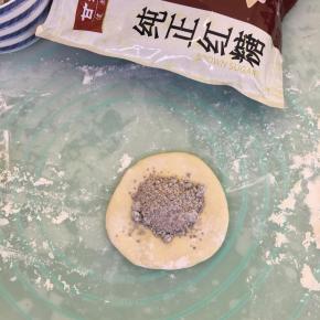 取一个面团用手按扁，放入1平勺馅料。