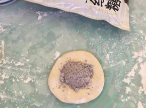 取一个面团用手按扁，放入1平勺馅料。