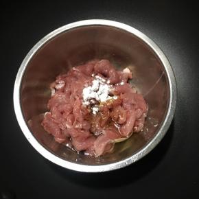 前腿肉切薄片，放入碗中，倒入酱油和1勺玉米油，加入玉米淀粉。