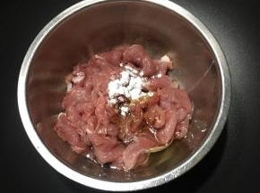 前腿肉切薄片，放入碗中，倒入酱油和1勺玉米油，加入玉米淀粉。