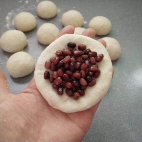 用擀面杖擀成四边薄中间厚的面片，放上一勺蜜豆