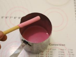 白巧克力滴入一滴红色食用油性色素，隔水融化，棒棒饼干条在巧克力内转一圈，只需要一半粘上巧克力。