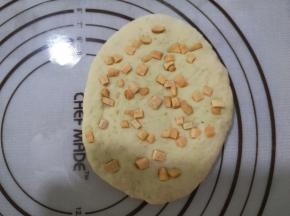 10、取出一个面团，擀成椭圆形，均匀地撒上红薯丁，再用擀面杖擀一下。