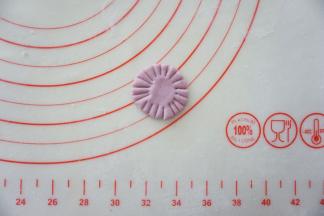 再取一小块另一个颜色的面团压扁，擀成小圆片，周围切出一圈花刀。
