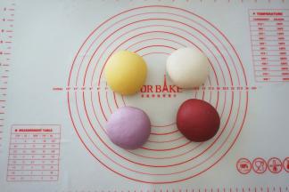 把面团平均分成四份，其中三份分别揉进南瓜粉、紫薯粉和红曲粉，分别揉成光滑的面团。