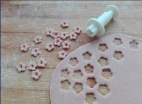 也可以用红曲粉调成淡粉色，同样擀薄，用模具压出小花，如图所示。