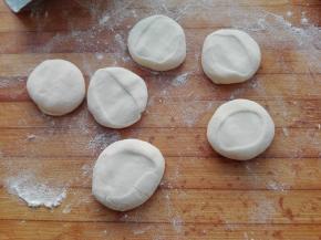 将醒发好的面团，取出放在案板上，搓成长条，切成小剂子，我每个剂子大约在18－19克左右，将其按扁，如图所示。