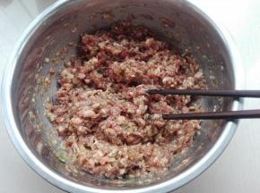 面团发酵的期间，我们来制作馅料部分：将肉跺碎成泥，放入葱沫、姜泥、花生油、味极鲜、糖，用筷子按一个方向将其搅拌均匀，先放置一旁腌一下。