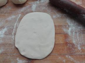 取其分好的剂子，用擀面杖将其擀成中间稍微有点厚，周边有点薄的包子皮，如图所示。