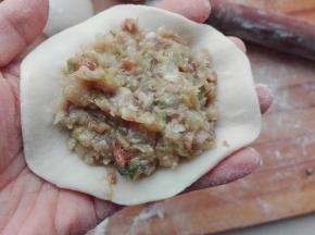 在擀好的包子里上，放入适量的馅料，如图所示。