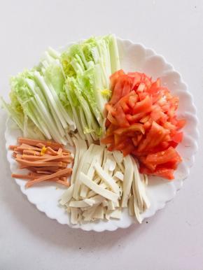 把所需的材料准备好：
白菜洗净切成丝，火腿肠切成丝，嫩豆腐也要切成丝，西红柿切成小丁儿备用。