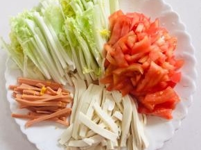 把所需的材料准备好：
白菜洗净切成丝，火腿肠切成丝，嫩豆腐也要切成丝，西红柿切成小丁儿备用。