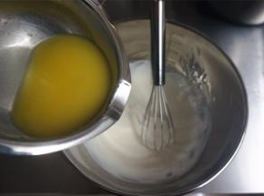 黄油隔热水加热融化后，慢慢倒入到奶酪糊中，边倒边搅拌均匀。