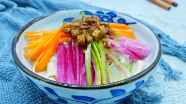 面条放入碗里，码上配菜、舀两勺炸酱。