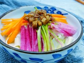 面条放入碗里，码上配菜、舀两勺炸酱。