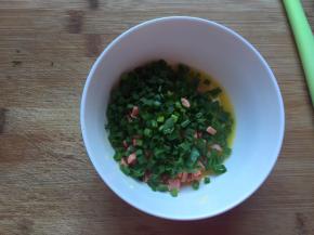 趁二次发酵的时间，做馅料，将黄油软化成液体，加入香葱和切好的火腿肠，搅拌均匀，冬天黄油一会就会凝固