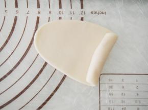 将水油皮擀成牛舌状，从一端卷起来。