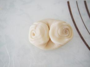 将面团用手指在中间压一下，两端往中间收，然后压扁。