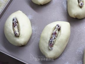 .发酵好的面团撒上椰子粉，用一把锋利的小刀在中间割出一道口子，深一点，挤上內馅。